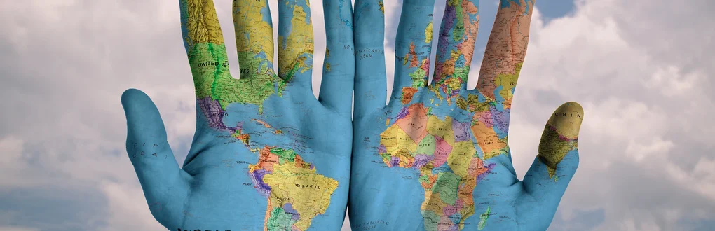Mapa mundo desenhado na palma de duas mãos