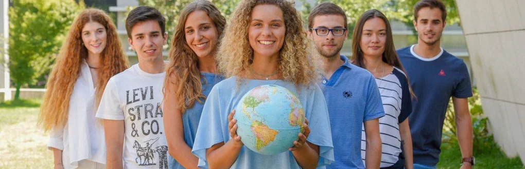 Grupo de estudantes em que uma das pessoas segura um globo terrestre