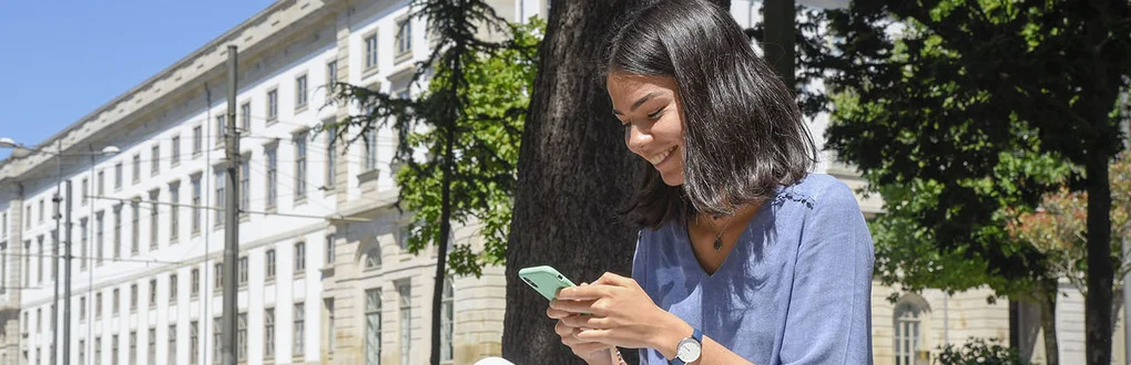 A student consulting her mobile phone in Jardim da Cordoaria, near the Rectory of the University of Porto