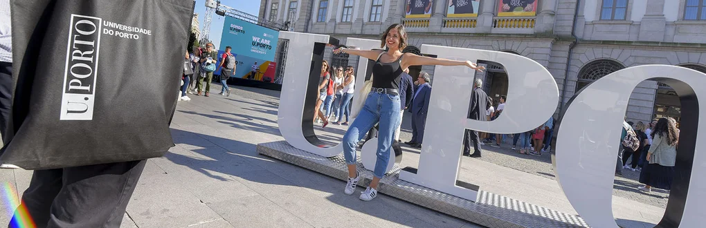 Nova estudante da U.Porto a posar para a fotografia junto às letras U.Porto em frente à Reitoria