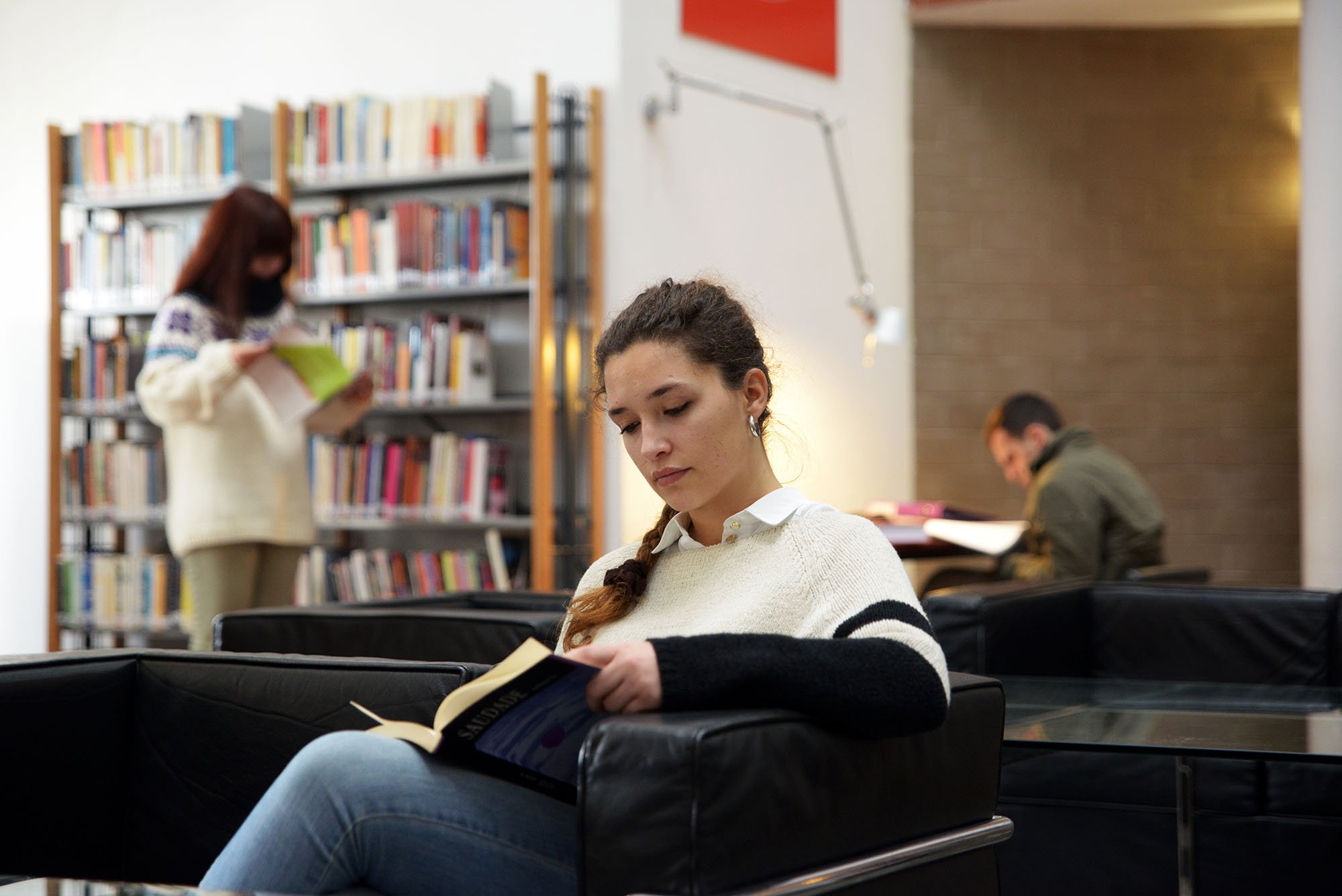 Uma estudante a ler um livro na biblioteca da FLUP